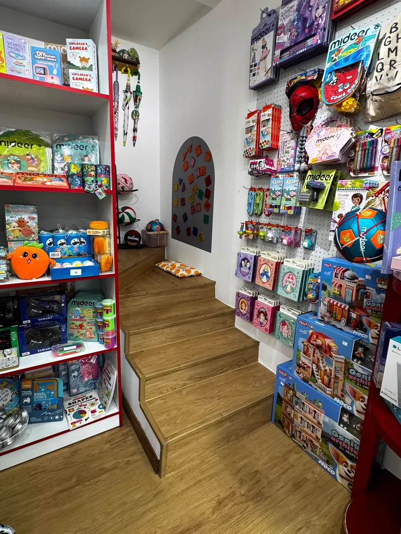 A side nook with wooden steps, between a shelf of Mideer boxes and a pegboard wall of boxed games and kits.